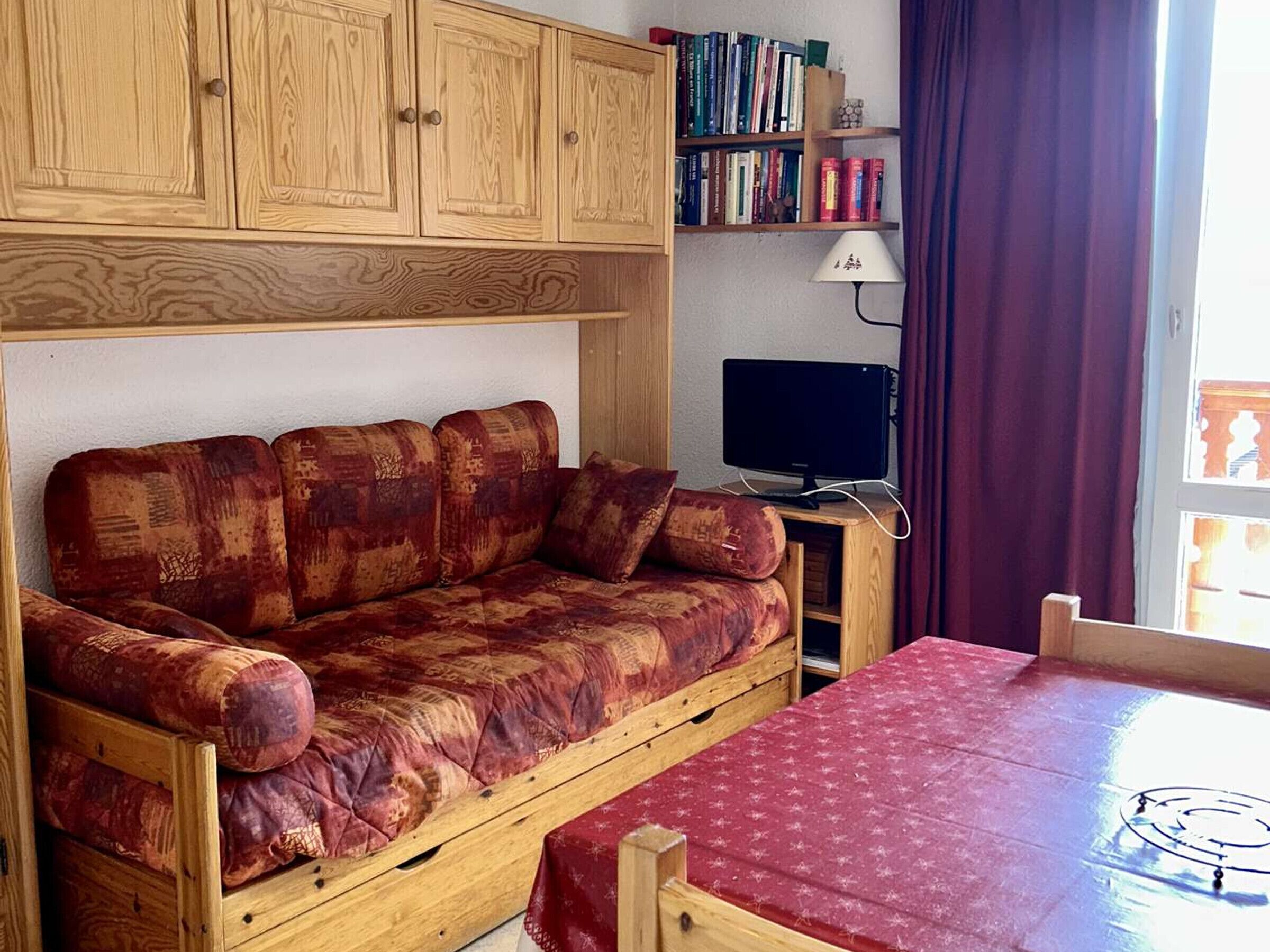 A compact living space with a sofa, a small table, a TV, and a bookshelf.