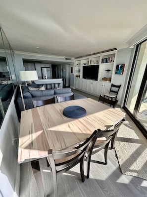A modern living room with a dining table, sofa, and kitchen area. - Oceanfront 3/3-This Is the One You Have Been Waiting For! All New+ Beach Locker! (Myrtle Beach)