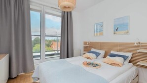 Un dormitorio con una cama grande, vistas al exterior y una ventana con cortinas.