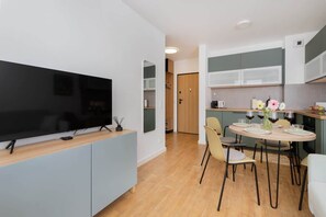 A modern kitchen with a dining area, a flat-screen TV, and a small table set for two. - Stylish Apartment with a Balcony | Gdansk Wrzeszcz (Gdansk)