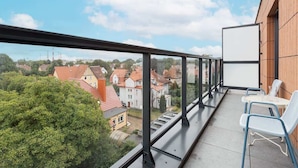 Un balcón con vistas a una zona residencial, una pizarra y una mesa con sillas.