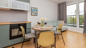 Un espacio habitable compacto con cocina, comedor y sofá junto a un ventanal grande.