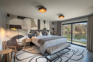 Quarto moderno com uma cama grande, um banco, uma cadeira e uma escrivaninha.