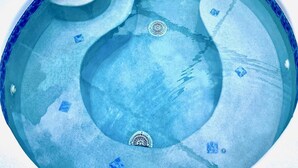 A swimming pool with multiple hot tubs and a drain cover.