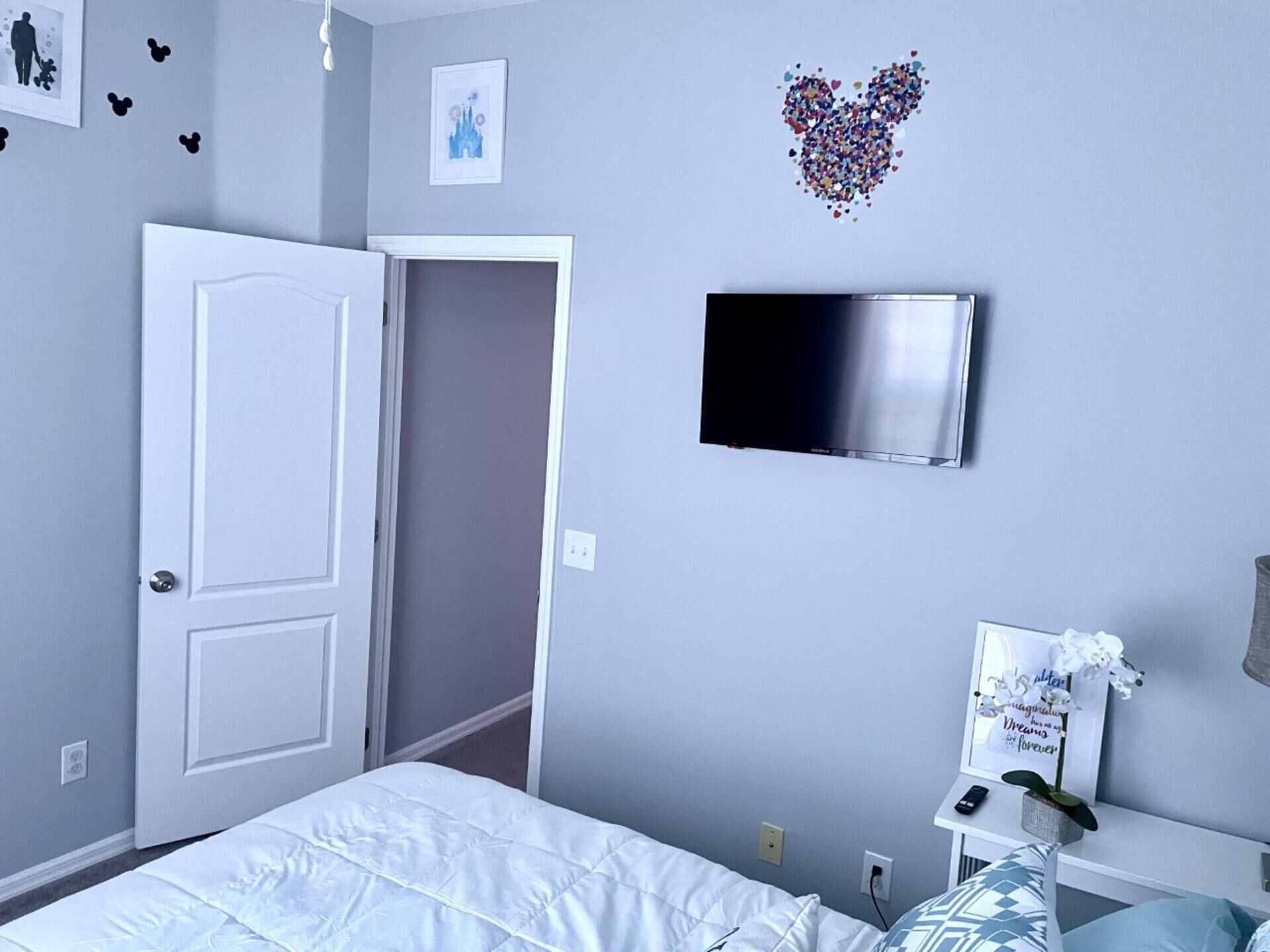 Ein Schlafzimmer mit Bett, Fernseher, Tür und Wand mit herzförmigen Verzierungen.