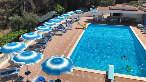 A swimming pool with lounge chairs and umbrellas, surrounded by trees. - Residence Jolly tra Peschici e Vieste (Peschici)