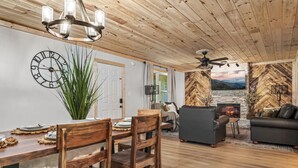 A cozy living room with a fireplace, a dining area with wooden furniture, and a large plant.