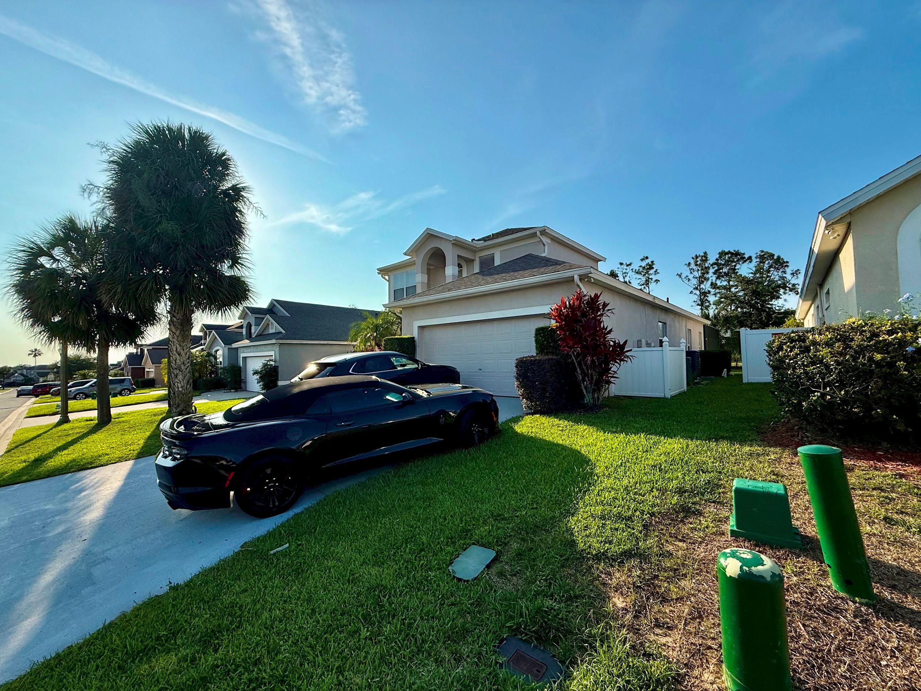 A residential area with a house, a driveway, and a parked sports car.