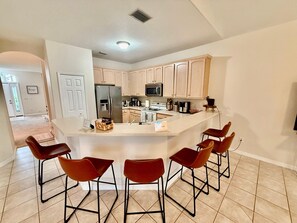A modern kitchen with a large island, bar stools, and stainless steel appliances.