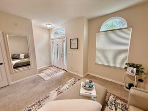 A spacious living room with a large mirror, a cozy seating area, and a decorative bowl on a side table. - Grand Family House With Private Pool Near Disney Parks (Davenport)