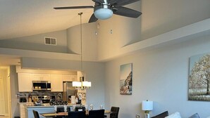 A modern living room with a grey sofa, a coffee table, and a dining area with a chandelier. - Grand Executive 3BD Condo Apartment Near Disney Parks 4 (Kissimmee)