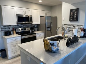 A modern kitchen with stainless steel appliances, white cabinetry, and a granite countertop. - Grand Executive 3BD Condo Apartment Near Disney Parks 4 (Kissimmee)