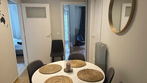 Un coin repas avec une table ronde, quatre sets de table en fibres tressées et des chaises noires.