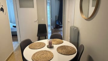 A dining area with a round table, four woven placemats, and black chairs.