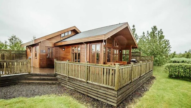 A wooden cabin with a deck and a covered porch. - Minni-Borgir Cabins (Borg)