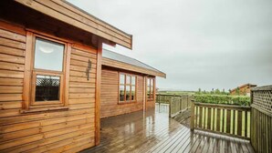A wooden cabin with a deck and large windows. - Minni-Borgir Cabins (Borg)