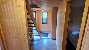 A wooden interior with a staircase, a bed, and a window. - Minni-Borgir Cabins (Borg)