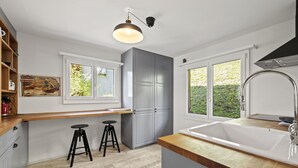Eine moderne Küche mit grauen Schränken, einer Holz Arbeitsplatte, einer Spüle und zwei Barhocker.