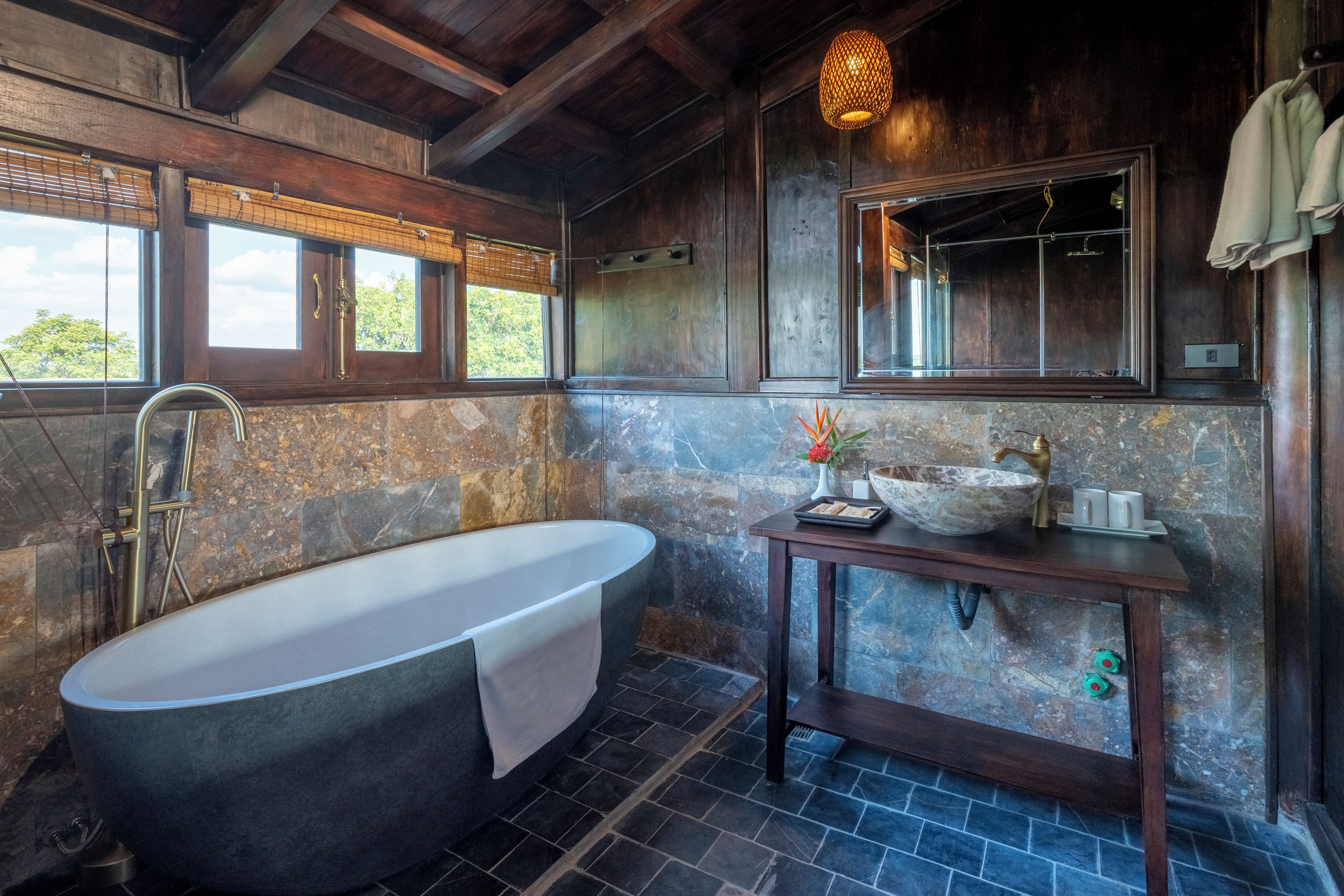 A bathroom with a freestanding bathtub, a wooden vanity, and a large mirror.