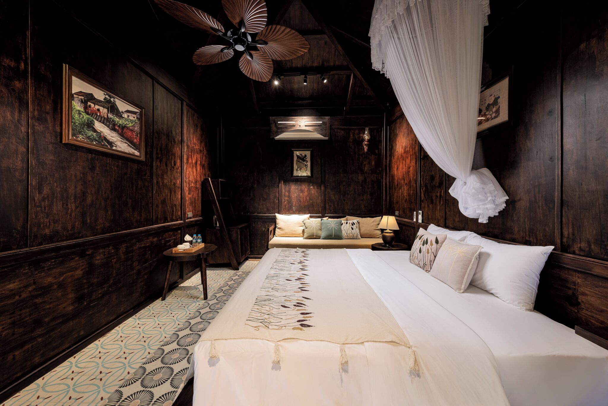 Een slaapkamer met een groot bed, houten wanden, een plafondventilator en een hemelbed.