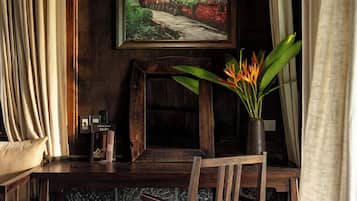 Une table de salle à manger en bois, accompagnée d’une chaise, d’un vase rempli de fleurs, d’un tableau encadré accroché au mur et d’un luminaire suspendu.
