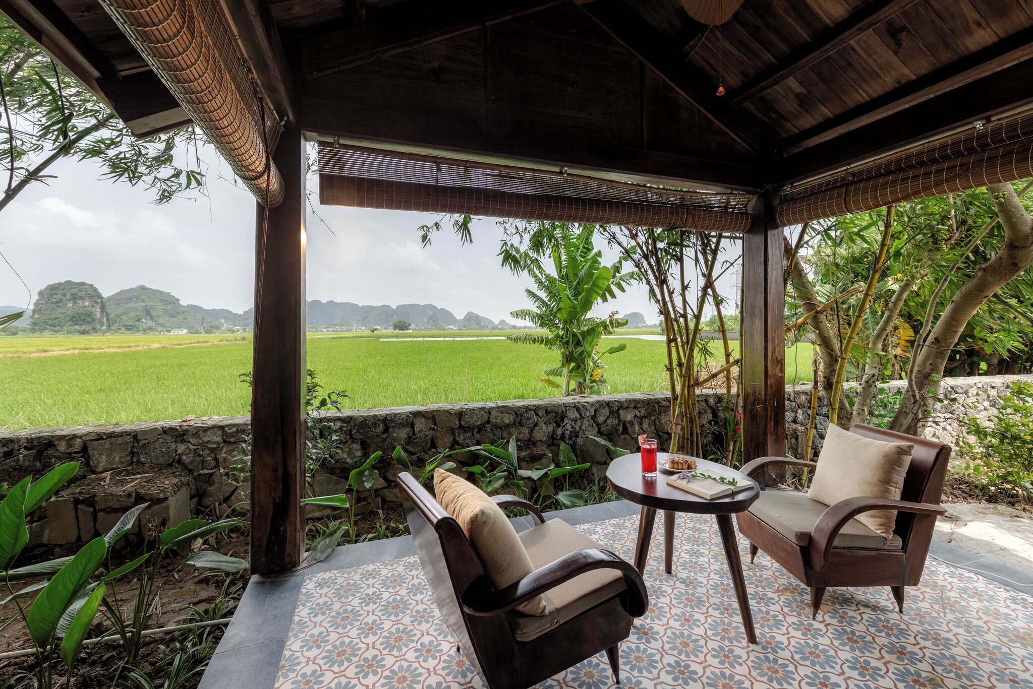 A covered outdoor seating area with a view of a green field and mountains.