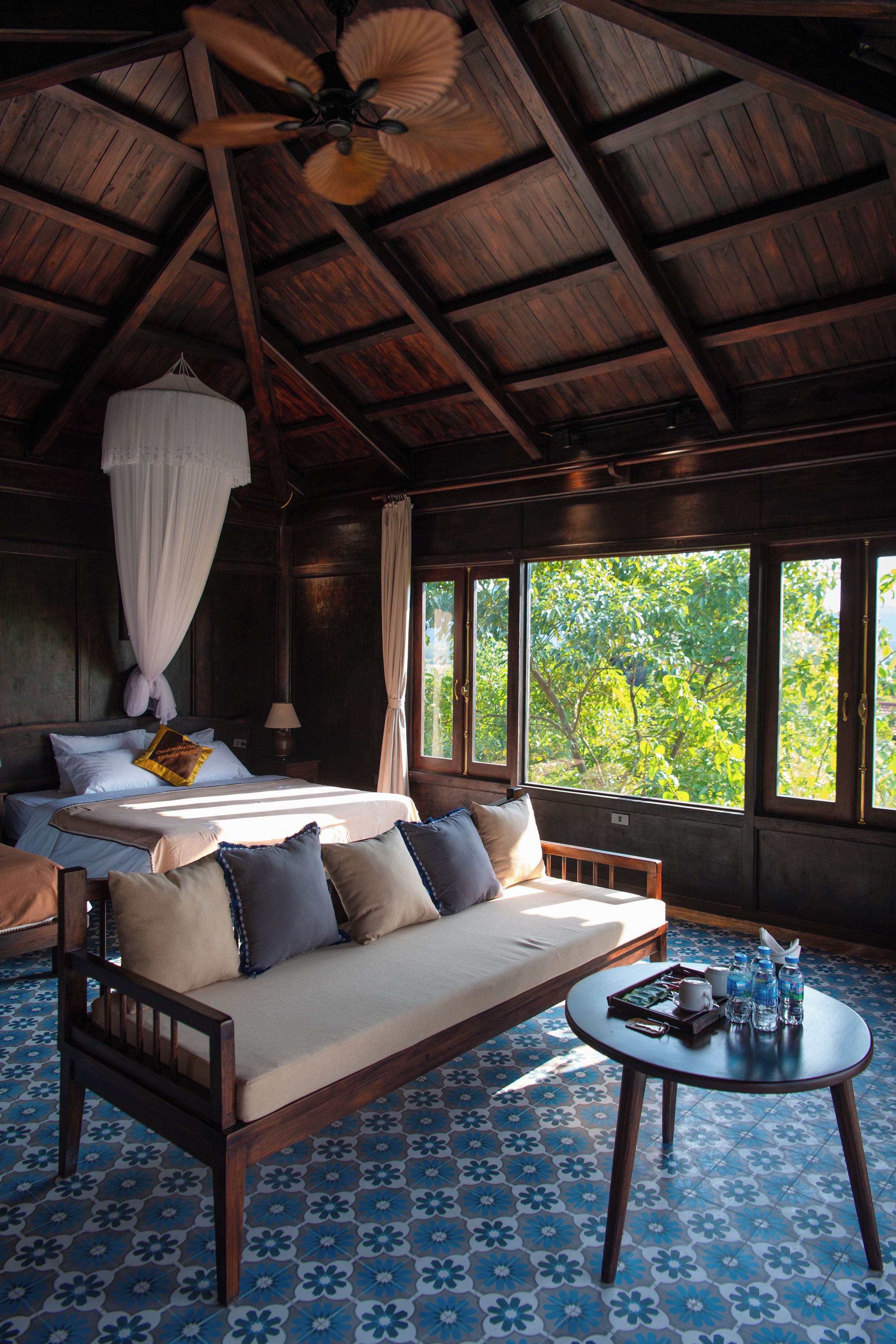 A room with a bed, sofa, and a round table with water bottles.