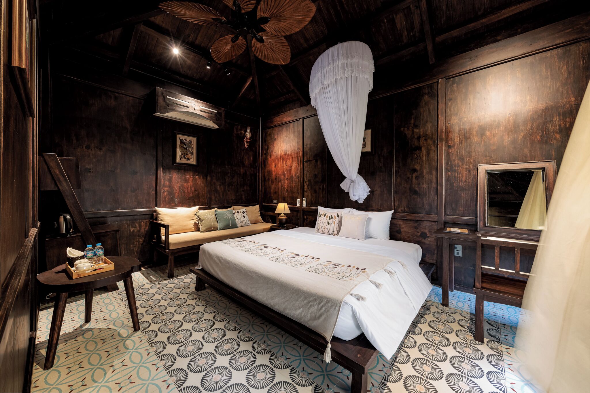 A room with a large bed, a wooden ceiling, a wall-mounted air conditioner, and a patterned floor.