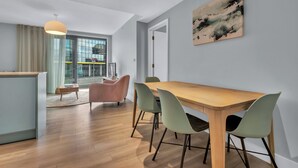 Un comedor moderno con una mesa y sillas de madera, una lámpara colgante y un gran ventanal con cortinas.