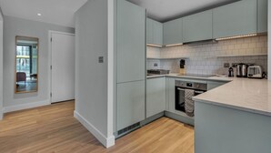Una cocina moderna con armarios grises, encimera blanca y suelo de madera.