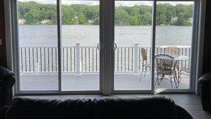 A room with a large sliding glass door leading to a balcony with a view of a lake and greenery.