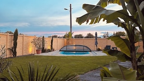 Patio con piscina, pared de ladrillo y diversas plantas.