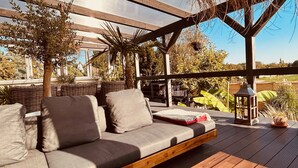 Un espacio al aire libre con un banco de madera y un sofá con cojines.