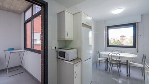 A compact kitchen with a microwave, refrigerator, and a small dining table with chairs.