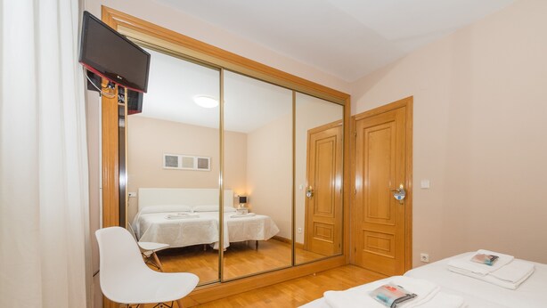 A bedroom with a large mirror, a bed, a chair, and a bedside table. - Espacioso Apartamento en Yamaguchi (Pamplona)