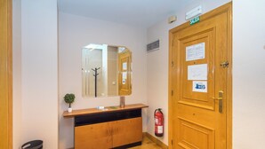 A reception area with a wooden desk, a mirror, a fire extinguisher, and a door labeled "SALIDA". - Espacioso Apartamento en Yamaguchi (Pamplona)