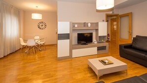 A modern living room with a flat-screen TV, a fireplace, a sofa, a coffee table, and a dining area with chairs. - Espacioso Apartamento en Yamaguchi (Pamplona)