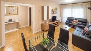 Ein modernes Wohnzimmer mit einem Glastisch, einer schwarzen Ledersofa und einem Fernseher.