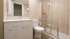 A modern bathroom with a glass-enclosed shower, a white sink, and a toilet.