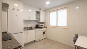 A compact kitchen with white cabinets, a microwave, a dishwasher, and a washing machine.