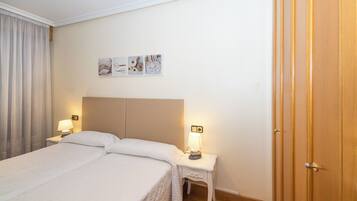 Una habitación de hotel con una cama grande, dos mesitas de noche con lámparas, un armario de madera y obras de arte en la pared.