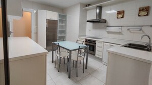 Eine moderne Küche mit weißen Schränken, einem Edelstahl-Kühlschrank, einem Gasherd und einer Spüle.