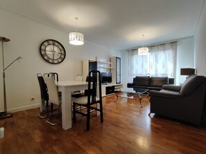 Ein modernes Wohnzimmer mit Essbereich, einem Flachbildfernseher und einer Couch.