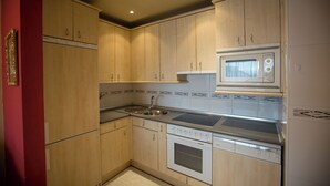 A compact kitchen with wooden cabinets, a built-in microwave, a dishwasher, and a sink.