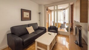 Ein Wohnzimmer mit einem schwarzen Ledersofa, einem weißen Couchtisch und einem Fernseher.