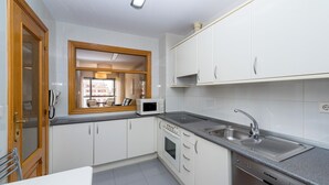 A compact kitchen with white cabinets, a microwave, a sink, and a dishwasher. - Apartamento Zona Clínica Universitaria (Pamplona)
