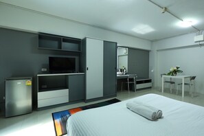 A modern hotel room with a bed, a desk, a television, and a minibar. - The trust ville (Bangkok)