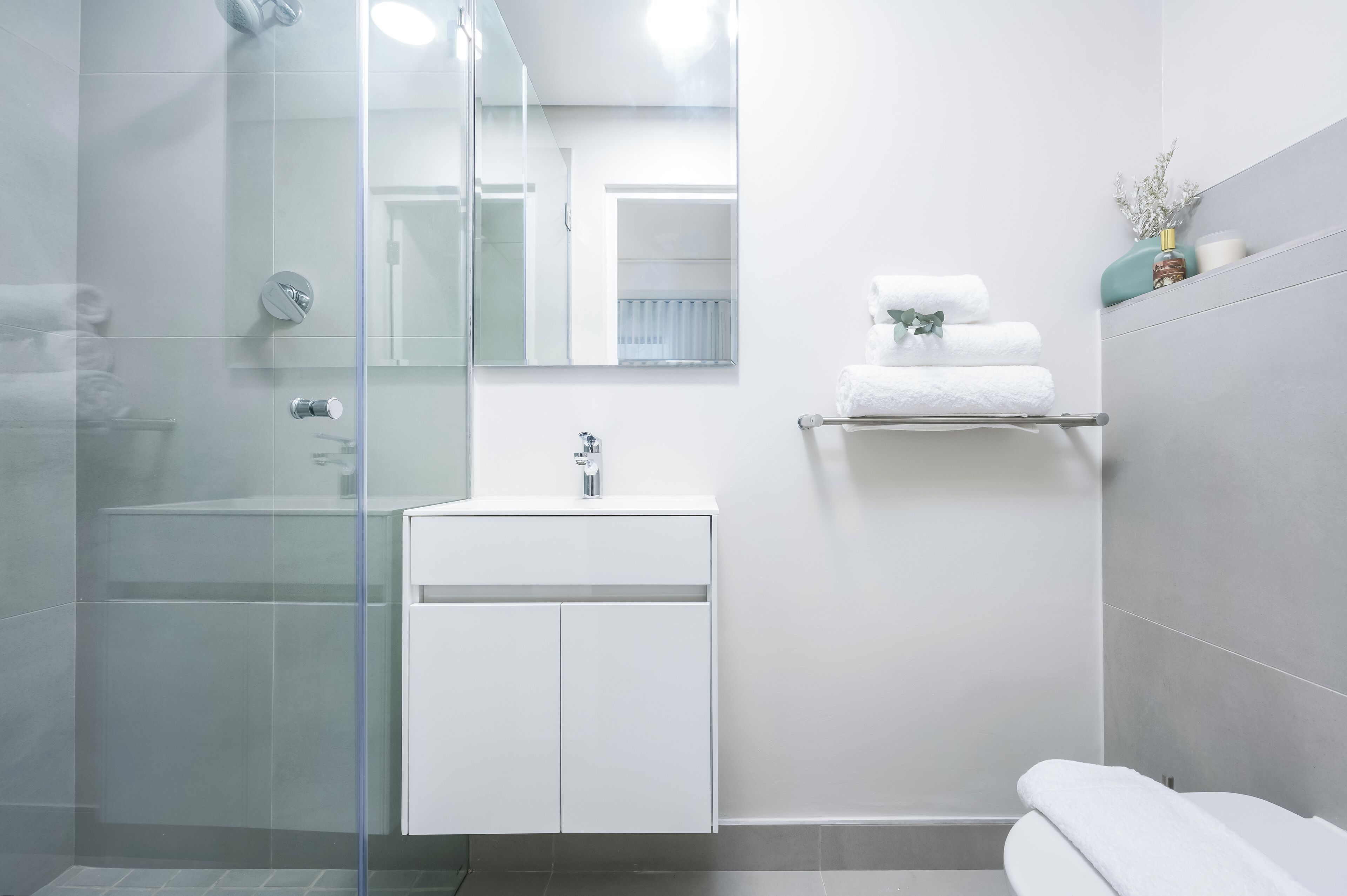 Un bagno moderno con box doccia in vetro, un lavandino bianco con rubinetto e un water.