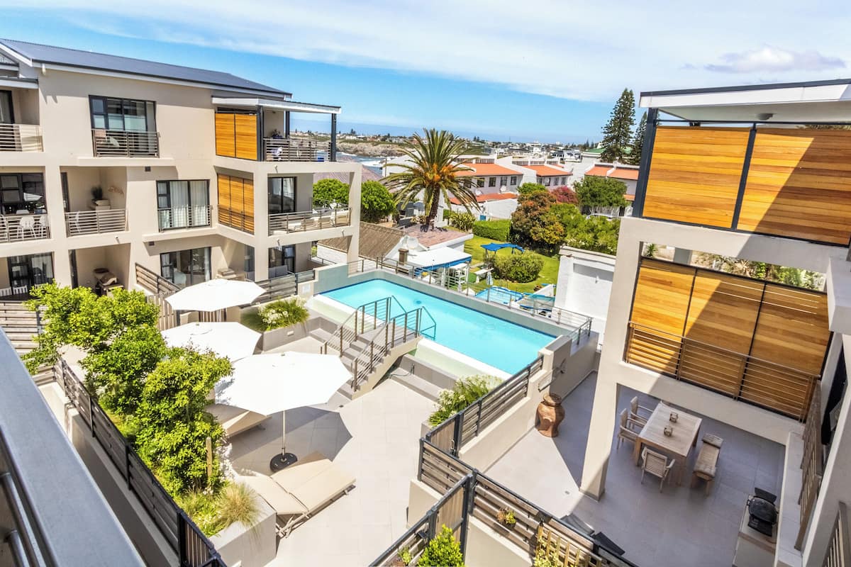 Un immeuble d’appartements moderne doté d’une piscine sur le toit, d’un espace de détente extérieur et offrant une vue sur l’océan.