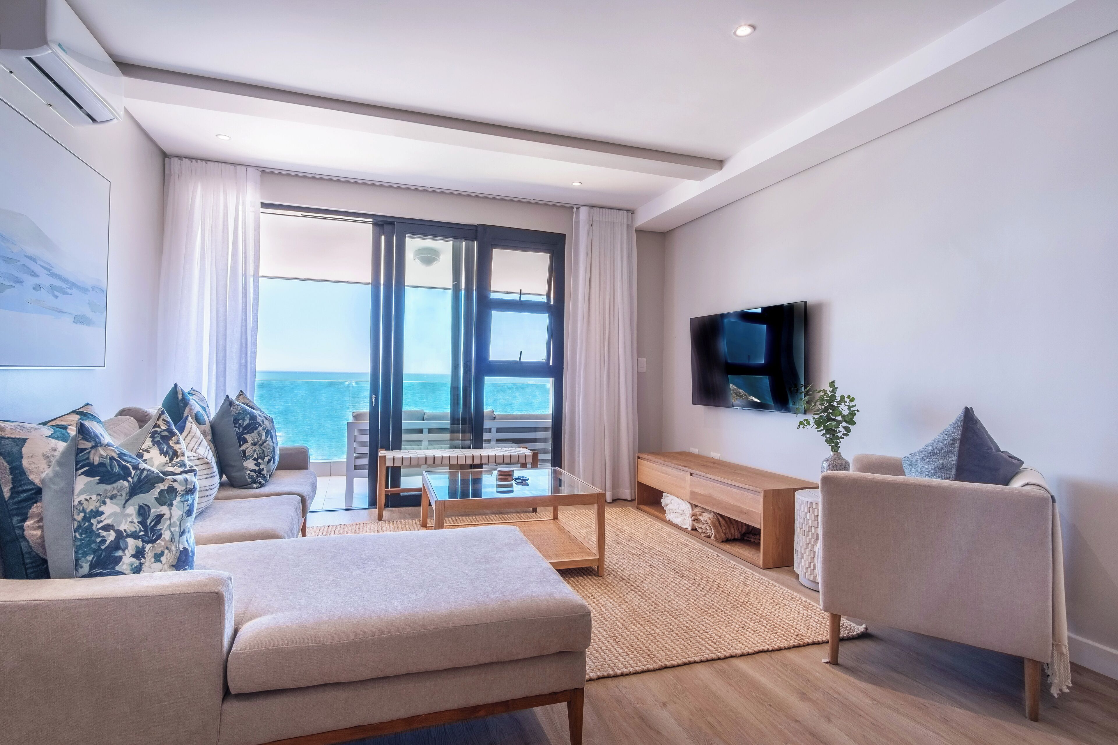 A modern living room with a sofa, a coffee table, and a TV mounted on the wall.